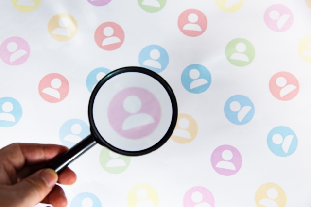 虫眼鏡で人を覗き見る手