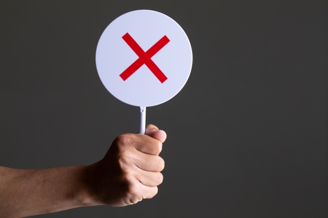 バツの札を持つ手