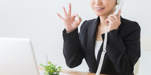 電話をしながらオーケーサインをする女性