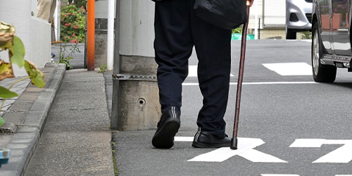 杖をついて歩く老人