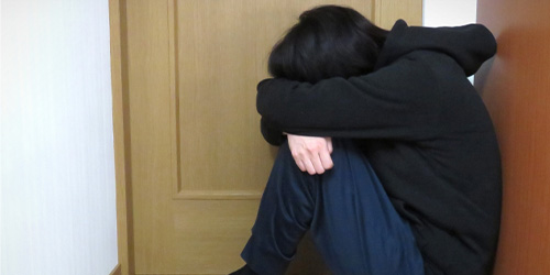 部屋の隅にうずくまる人